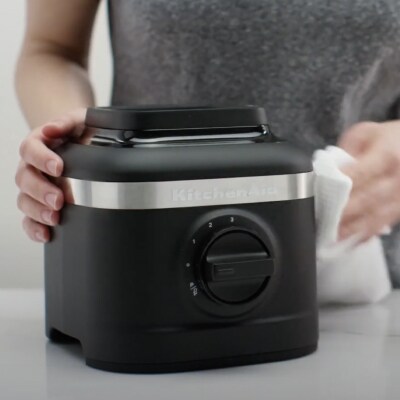 Person cleaning black KitchenAid® blender base